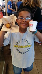 Student holding hot cocoa and donut from Van Buren Elementary.