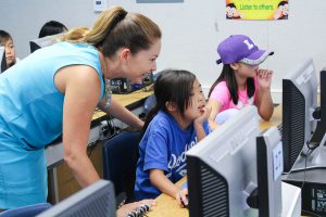 Principal Lisa White looks at a student's work in Summer Enrichment's "The Art of Animation" class.