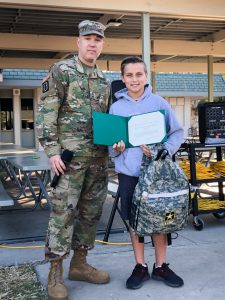 Sergeant Wroblewski presents Glenknoll Elementary School student Alex Bartolo with a certificate of achievement and special United States Army school supplies for his efforts raising donations for the Placentia-Yorba Linda Unified School District McKinney Vento Program.