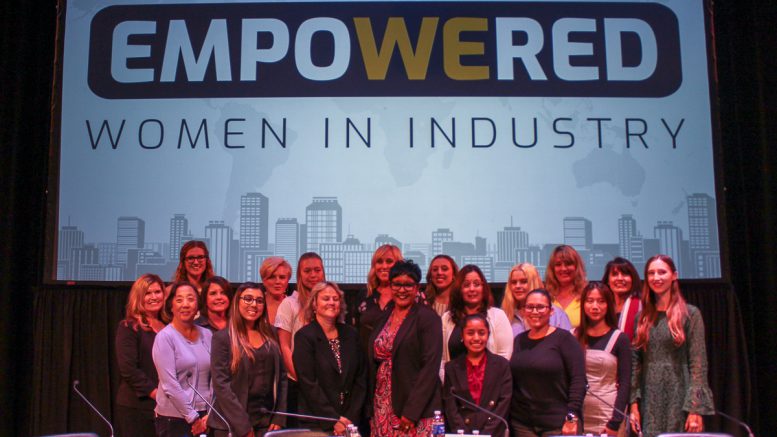 Women in Industry panelists and student moderators pose for a photo on stage.
