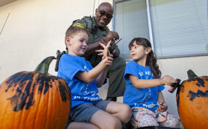 Sgt. Ade Olukoju of the Orange County SheriffÕs Dept. watches as students at Travis Ranch Elementary School paint Halloween pumpkins in Yorba Linda on Tuesday, October 22, 2019. The pumpkins were provided by the SheriffÕs Department. (Photo by Paul Rodriguez)