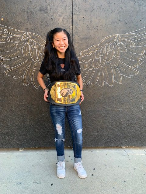 EDHS Senior Diana Van Winkle poses on her school campus holding the We Are One black and gold belt